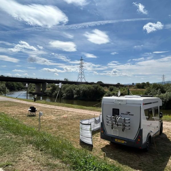 Camper van by river under blue sky